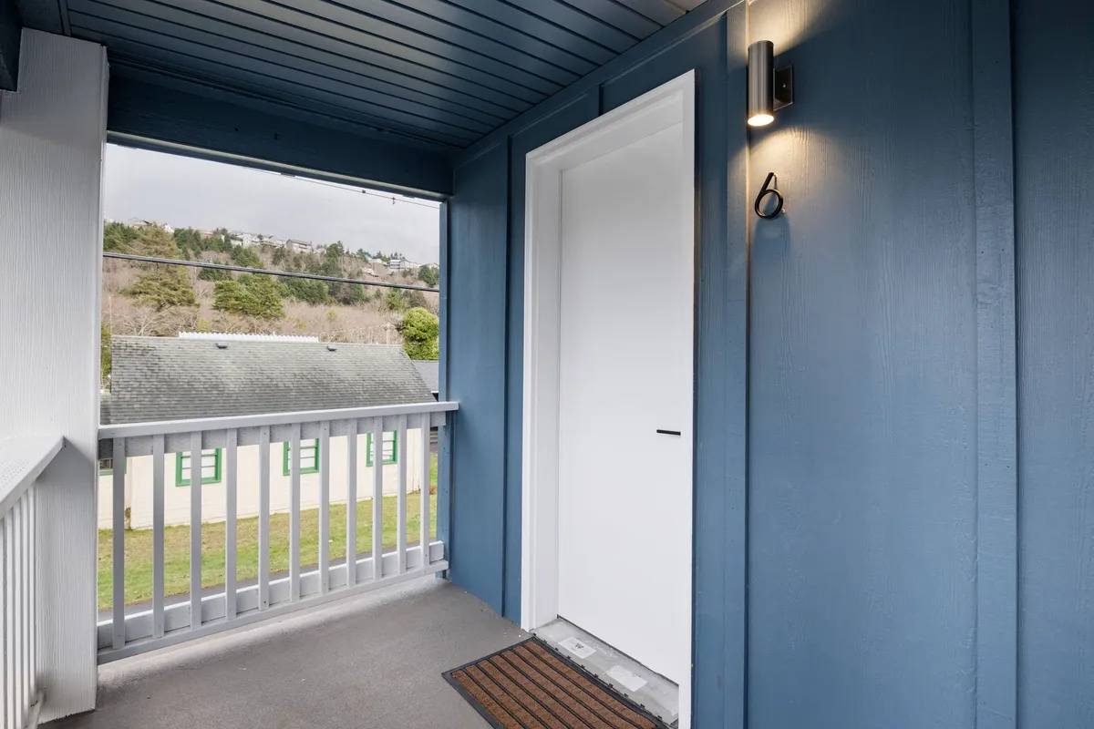 This interior image features blue walls, a crisp white door, and a glimpse of the outdoors visible through the entry, evoking a welcoming and tranquil atmosphere. Though primarily an interior shot, the visible outdoor view through the door hints at the connection between the comfort of the remodeled unit and the adventures waiting just outside.